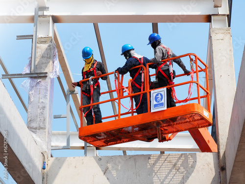 construction worker at construction site using lifting boom machinery