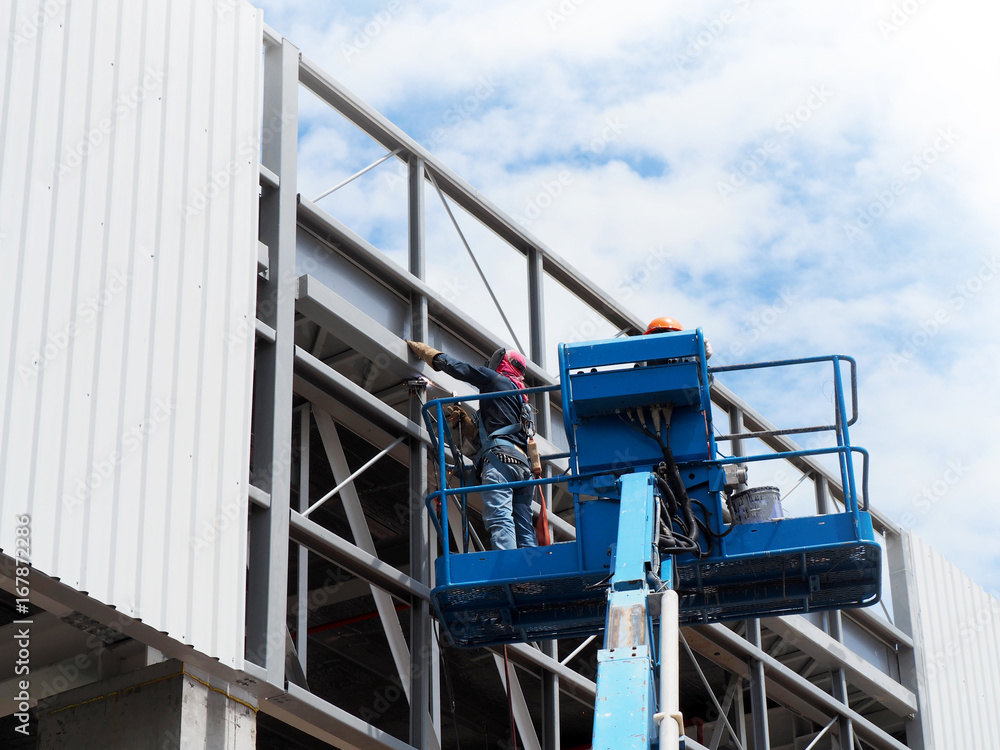 Naklejka premium construction worker at construction site using lifting boom machinery