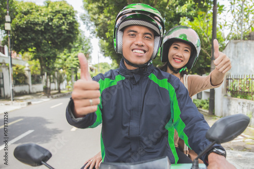 commercial motorcycle taxi driver and his passenger showing thumb up