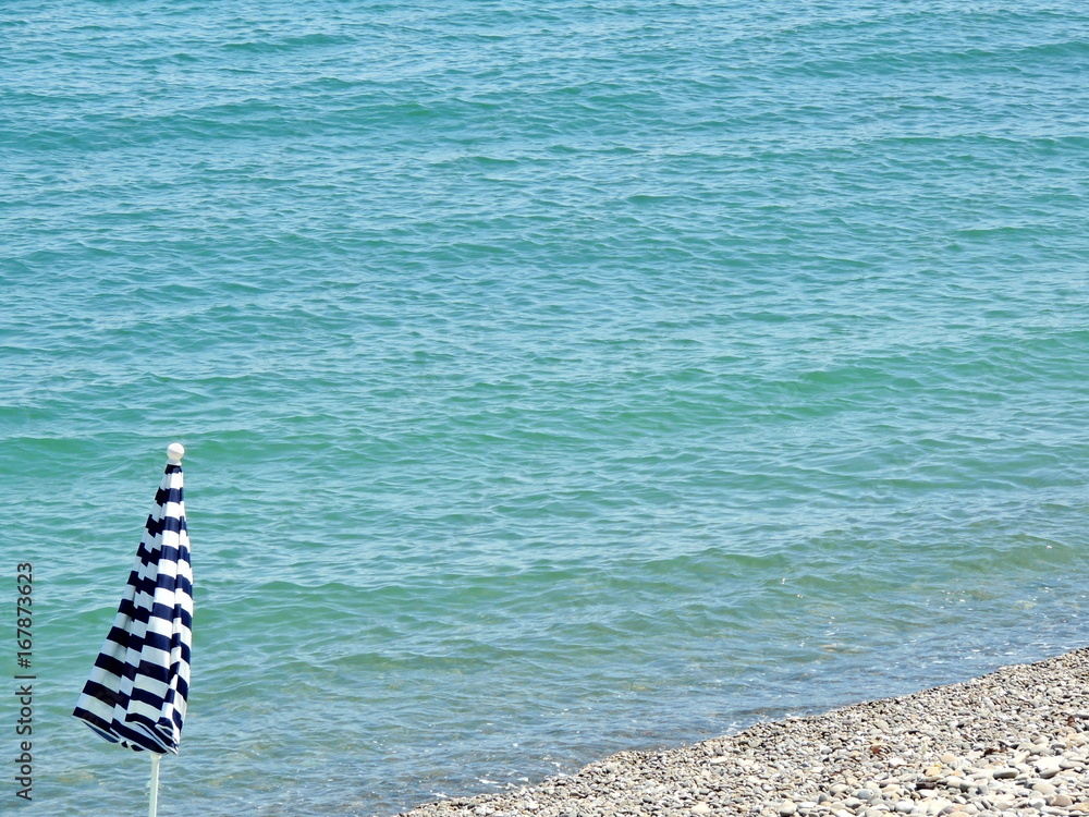 Closed beach umbrella on the beach. Marine background with copy space for text. Closed beach umbrella on the beach. Marine background with copy space for text.