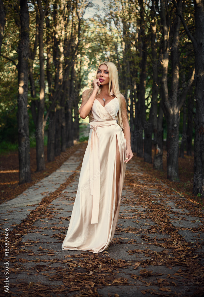 Girl in a long dress in the park. Blonde. Summer.