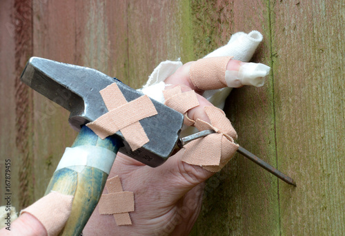 Canvas-taulu Ten thumbs, heavily injured homeworker tries to hammer a bent nail in a wall