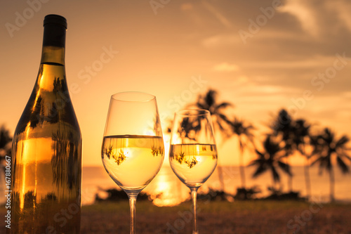 Fototapeta Naklejka Na Ścianę i Meble -  Pair of wine glasses against a beautiful sunset beach setting. Romantic getaway for two concept. 