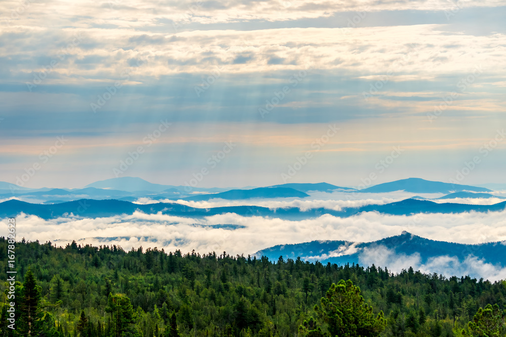 Breathtaking sunrise and mist over the tops of mountains and woods
