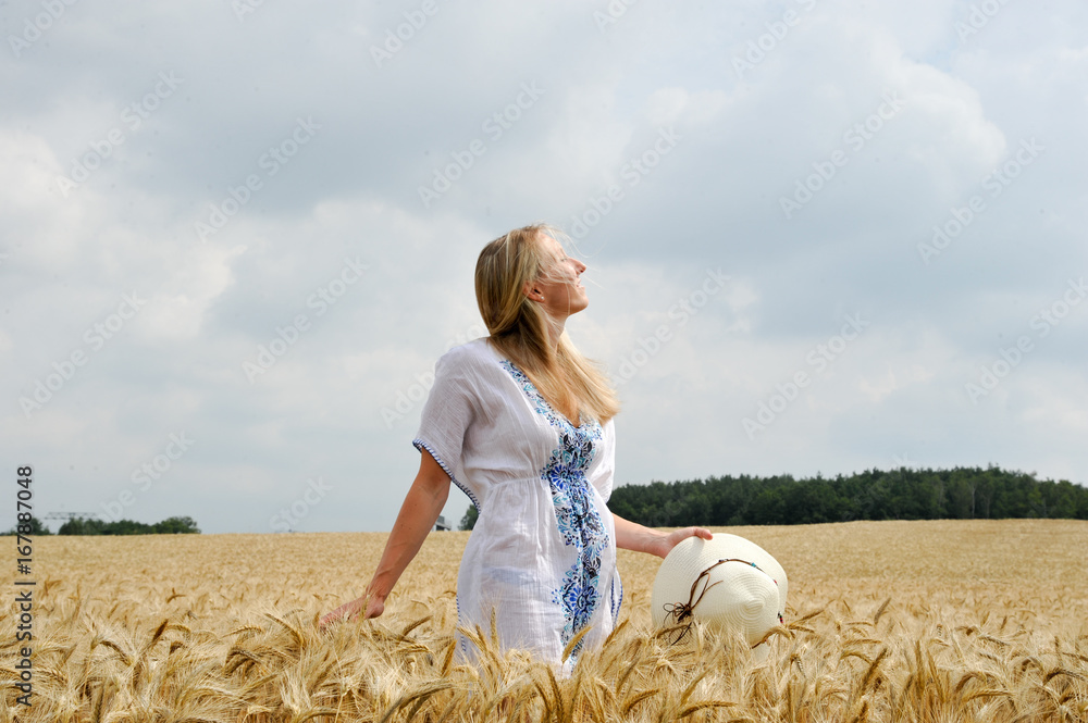 Frau im sommerlichen Kornfeld mit Kleid und Strohhut Frau im sommerlichen Kornfeld mit Kleid und Strohhut