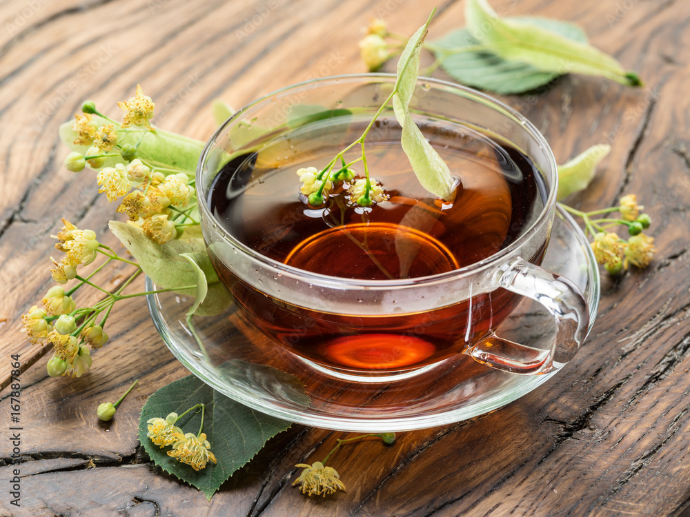 Cup of linden tea and lime flowers on the wooden table. Cup of linden tea and lime flowers on the wooden table.