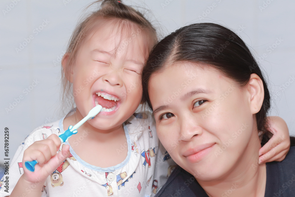 Little girl brushing her teeth with mother on white background Little girl brushing her teeth with mother on white background