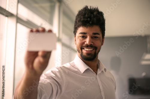 African man holding a blank business card. Focus on smile man. Space for copy.
