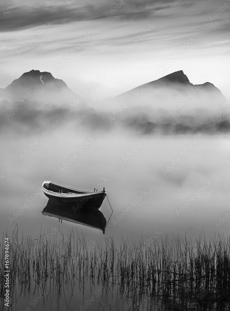 Fototapeta premium Bardzo spokojna letnia noc z drewnianą łodzią i mgłą w Lofoten, Norwegia