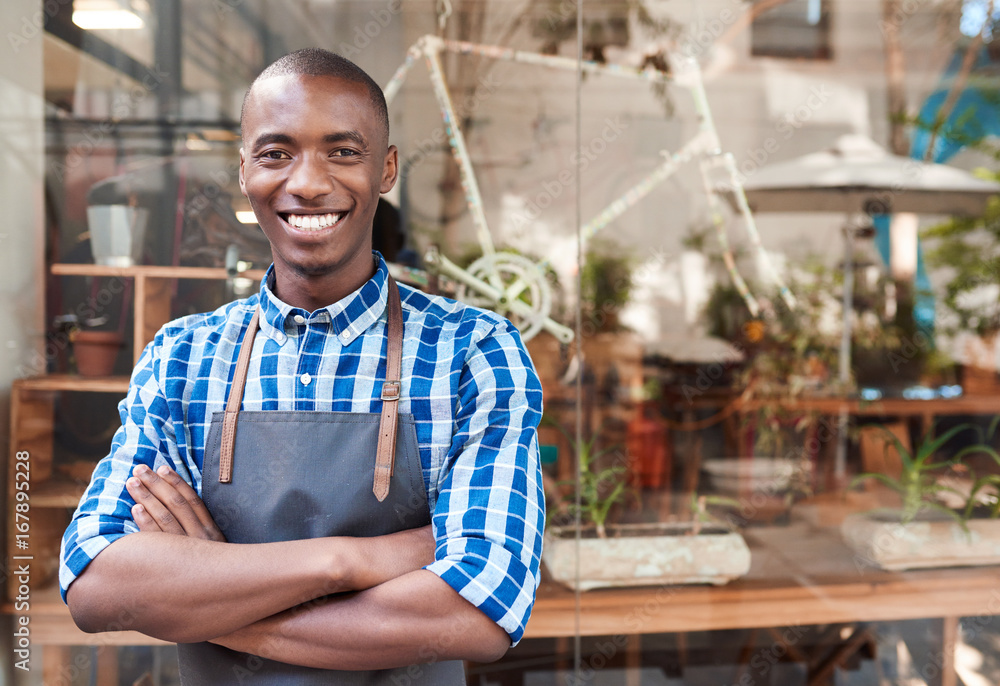 Smiling African entrepreneur standing behind a counter of his cafe Smiling African entrepreneur standing behind a counter of his cafe