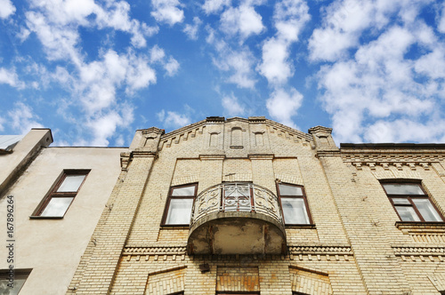 Look up at the ancient brick building with metal forged balconies on the background of cirrus clouds. Grodno, Belarus.