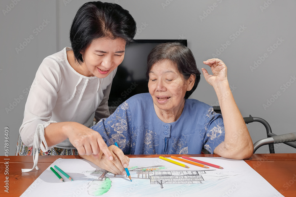 Elderly woman painting color on her drawing with daughter , hobby at home Elderly woman painting color on her drawing with daughter , hobby at home