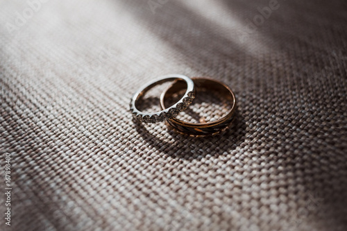 Golden wedding rings with sparkling stones lie on the chair