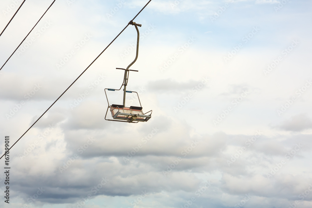 Empty chairlift with cloudy sky in the background Empty chairlift with cloudy sky in the background