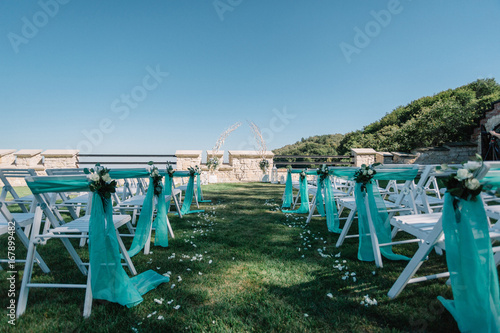 Chairs for guests stand on the lawn before a wedding altar