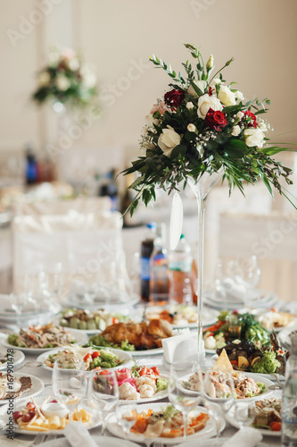 Tall vases with red and white flowers stand on the dinner tables