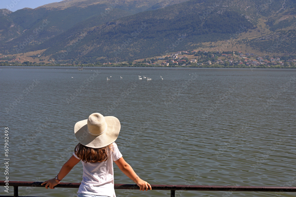 The girl watches the swans on the lake Ioannina Greece