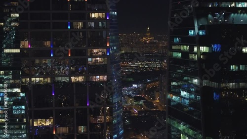 Unique Aerial flight around and approach to windows of Moscow City business center. Evening illumination. Offices from outside. Managers employees work. Quadcopter drone beautiful 4K shot
