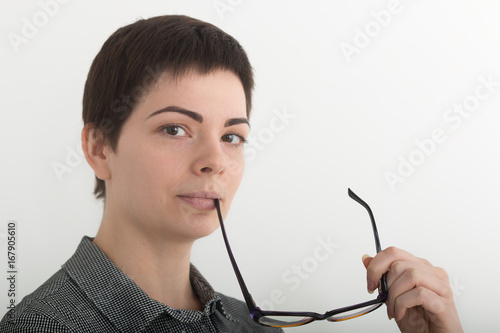 Young attractive girl in black and white plaid shirt seriously holding glasses near her mouth. Isolated on white background, mask included photo