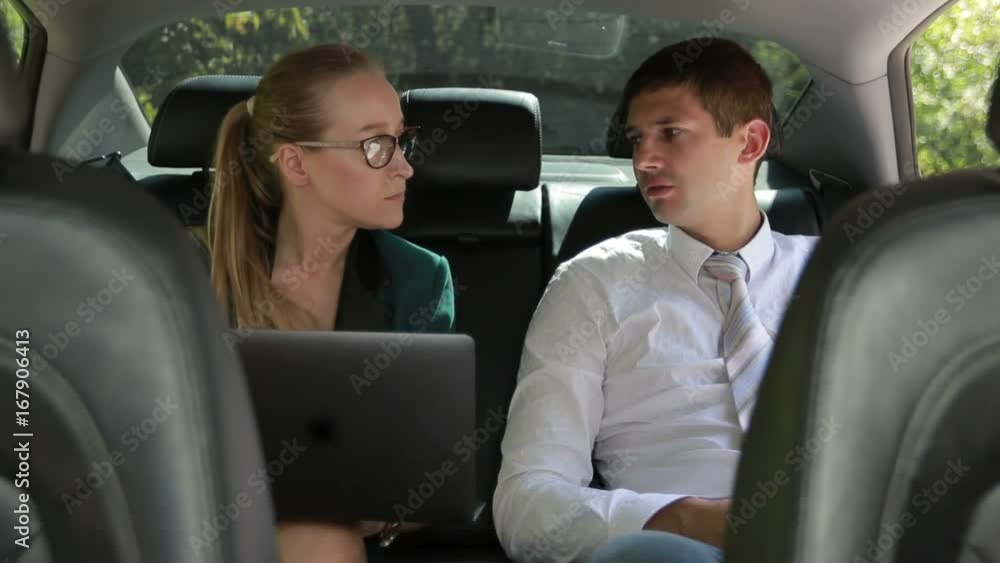 Two business colleagues working with laptop in car Two business colleagues working with laptop in car