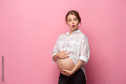 Fotografie, Obraz Young beautiful pregnant woman standing on pink background