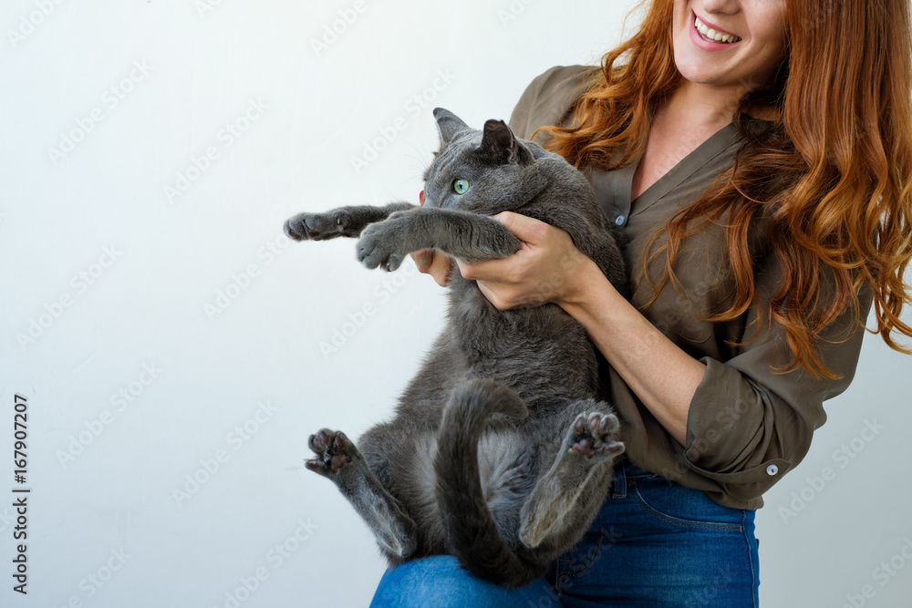 Pretty woman holding her russian blue cat in hands.