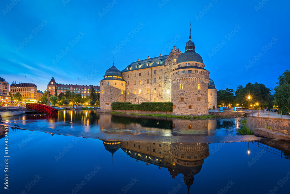 Medieval Orebro Castle reflecting in water in the evening in Orebro, Sweden