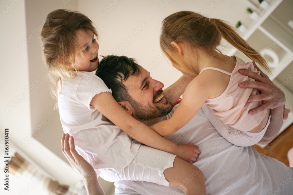 Happy father and little daughters spending time at home. Father and daughters playing at home. Little girl sitting on fathers shoulder. Happy father and little daughters spending time at home. Father and daughters playing at home. Little girl sitting on fathers shoulder.
