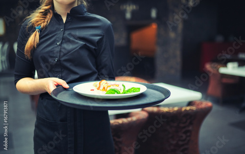 Waiters carrying plates with food, in a restaurant. photo