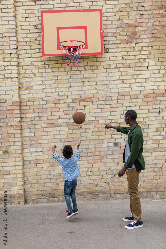adorable african-american father and son playing basketball together