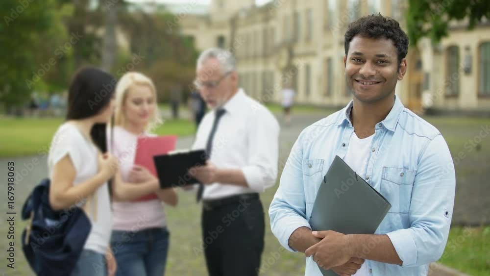 Happy Hispanic student standing near college and looking into camera, education Happy Hispanic student standing near college and looking into camera, education