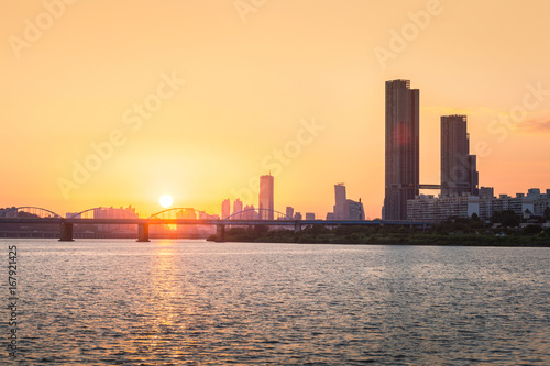 Sunsets behind the skyscrapers of yeouido and bridges across the Han River in Downtown Seoul, South Korea. © panyaphotograph