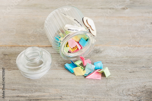 Glass Jar with Lid Off and Pastel Folded Notes Spilling Over