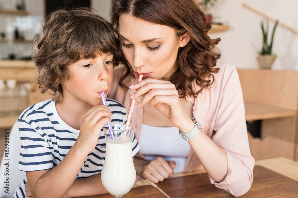 mother and son drinking milkshake together in cafe