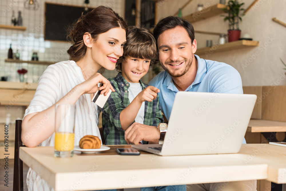 young family doing e-shopping with laptop while sitting in cafe young family doing e-shopping with laptop while sitting in cafe