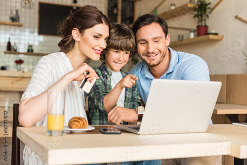 young family doing e-shopping with laptop while sitting in cafe