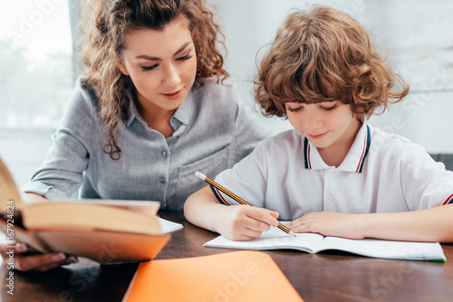 young mother and adorable son doing homework together