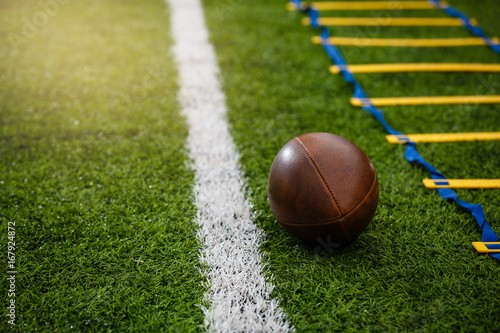Photo of an American football on a grass next to the touchline, shot from above.