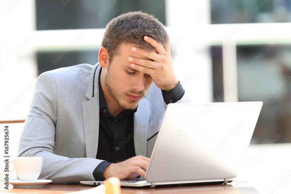 Worried executive on line in a coffee shop Worried executive on line in a coffee shop