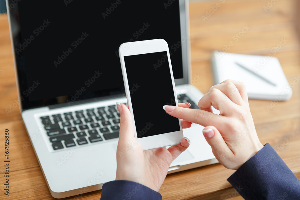 Female using laptop and smartphone, close up, side view,