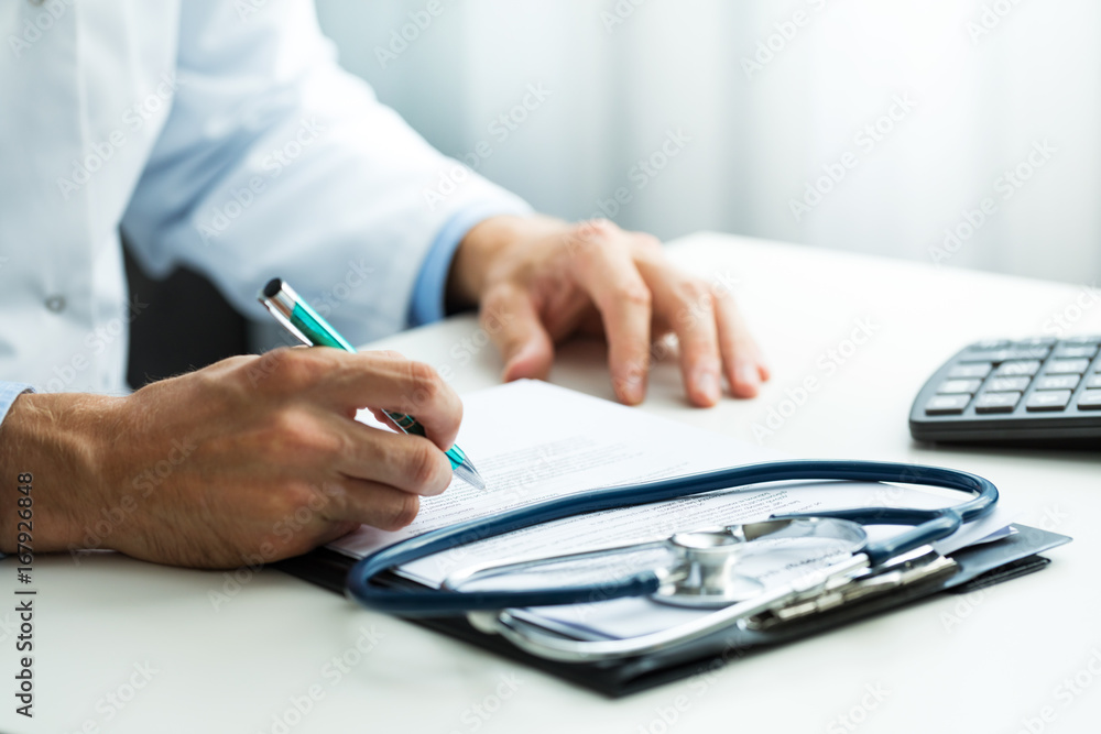 Fototapeta premium doctor writing prescription at desk in clinics office