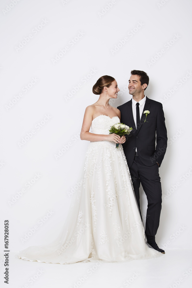 The handsome newlywed couple standing in white studio The handsome newlywed couple standing in white studio