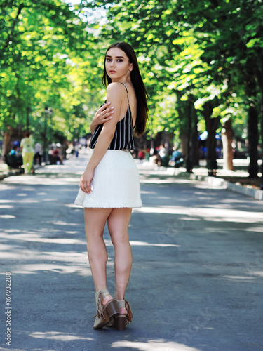 Young girl model posing at the park standing and looking back at camera © Sergii Mironenko