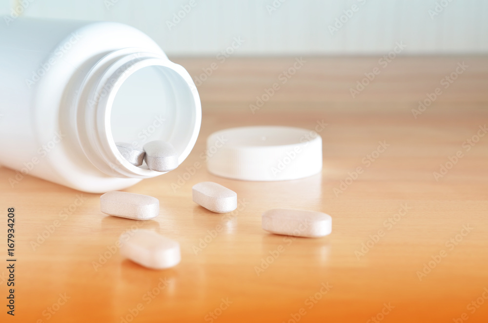 Pharmacy theme. White bottle of pills on a wooden surface. Closeup.