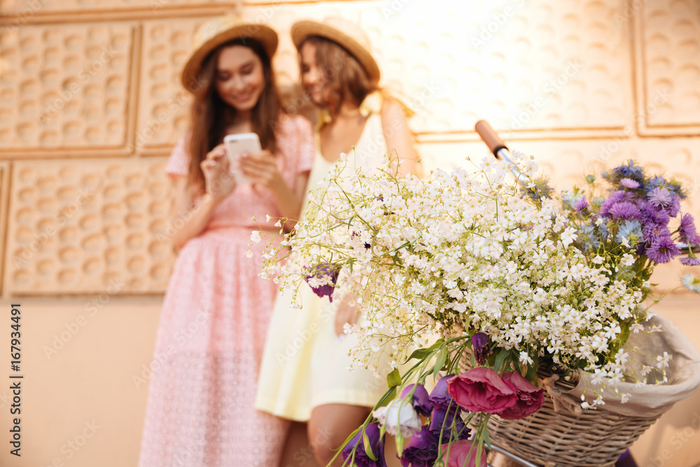 Young happy ladies standing outdoors using phone Young happy ladies standing outdoors using phone
