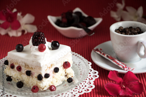 Ein Stück Sahnetorte mit Beeren und einen Tässchen Kaffee