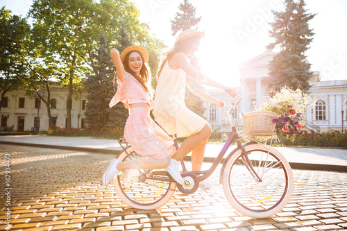 Young smiling ladies outdoors on bicycle