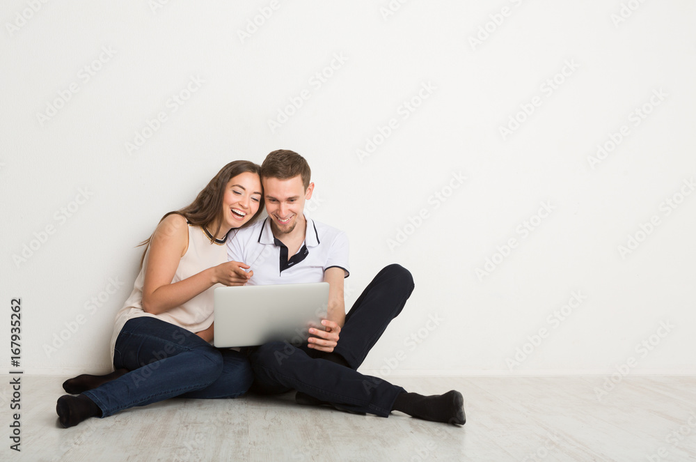 Cheerful couple using laptop at home, copy space Cheerful couple using laptop at home, copy space