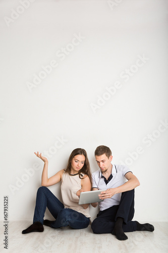 Shocked couple using laptop, sitting on floor