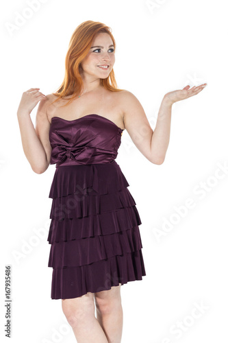 Young girl gesturing with hands for presentation. Redheaded girl wearing dark purple strapless dress.